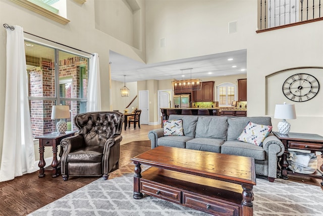 living room with a chandelier, a towering ceiling, and dark wood-type flooring