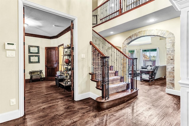 staircase with ornate columns, crown molding, a textured ceiling, and hardwood / wood-style flooring