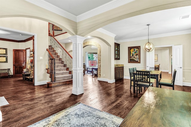 entrance foyer featuring dark hardwood / wood-style floors, ornate columns, crown molding, and a notable chandelier