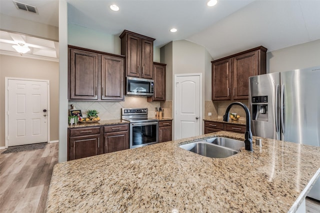 kitchen featuring backsplash, light hardwood / wood-style floors, sink, and stainless steel appliances