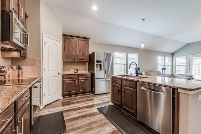 kitchen with sink, backsplash, vaulted ceiling, appliances with stainless steel finishes, and hardwood / wood-style flooring