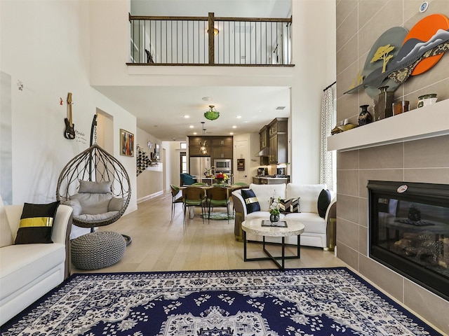 living room with hardwood / wood-style flooring, a high ceiling, and a fireplace