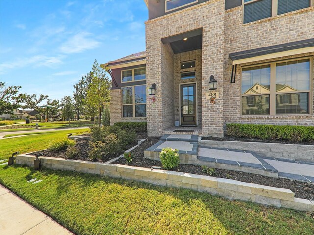 view of exterior entry with a lawn