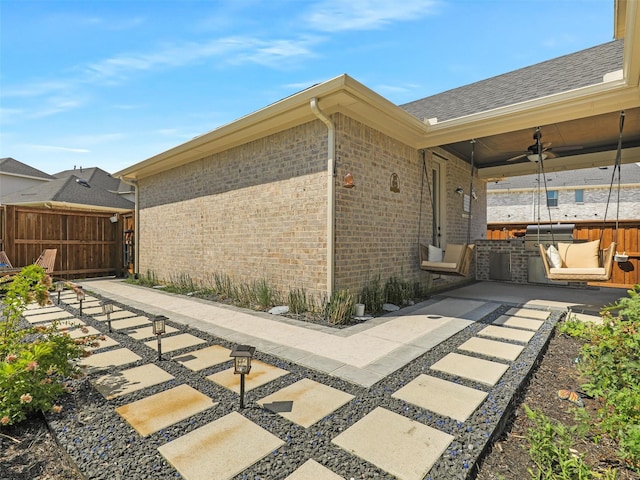 view of property exterior featuring ceiling fan, an outdoor kitchen, and a patio