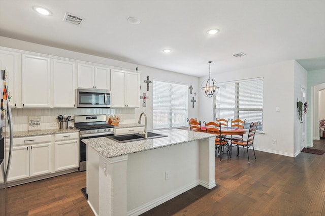 kitchen with dark wood-type flooring, decorative light fixtures, a center island with sink, white cabinets, and appliances with stainless steel finishes