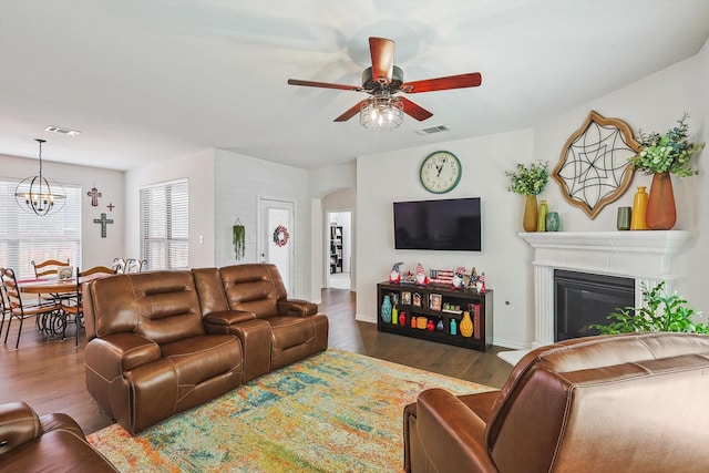 2133 Miramar Dr, Little Elm, TX 75068 - living room featuring a ceiling fan, dark wood-style flooring, a chandelier, arched walkways, and a glass covered fireplace