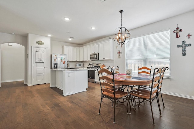 dining space with sink, dark hardwood / wood-style flooring, and an inviting chandelier