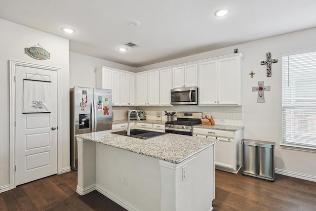 kitchen featuring stainless steel appliances, dark wood-type flooring, sink, white cabinetry, and an island with sink