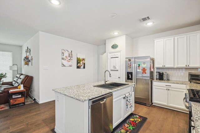 2133 Miramar Dr, Little Elm, TX 75068 - kitchen with stainless steel appliances, dark wood finished floors, a kitchen island with sink, white cabinetry, and tasteful backsplash