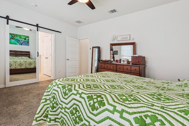 bedroom with a barn door, ceiling fan, and carpet