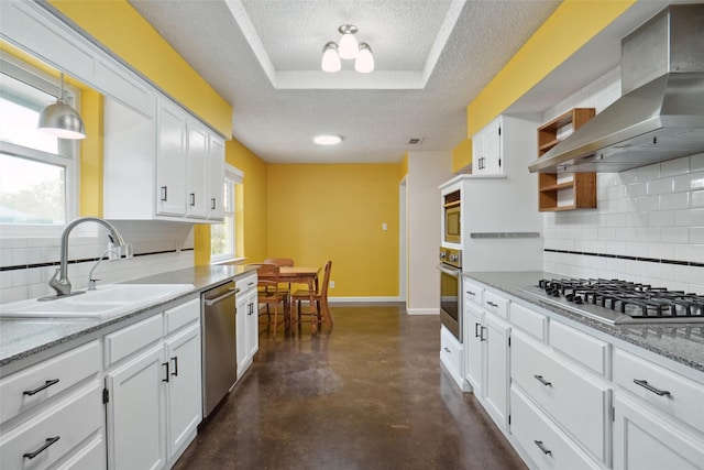 kitchen featuring pendant lighting, white cabinetry, sink, stainless steel appliances, and wall chimney exhaust hood