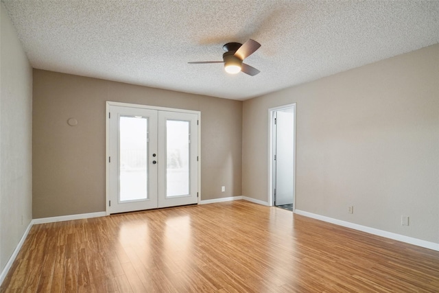 empty room featuring a textured ceiling, light hardwood / wood-style flooring, french doors, and ceiling fan