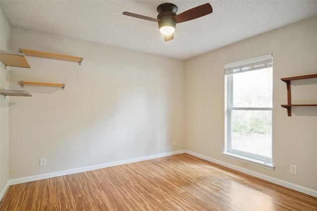 unfurnished room featuring a wealth of natural light, a textured ceiling, and light hardwood / wood-style floors