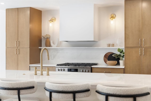 kitchen with a kitchen bar, tasteful backsplash, and stainless steel range oven