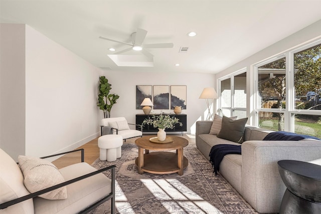 living room with hardwood / wood-style floors, a skylight, and ceiling fan