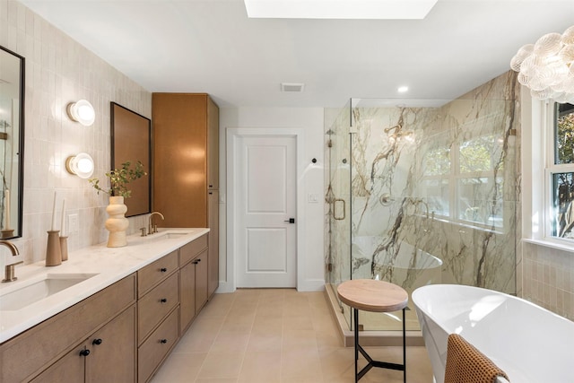 bathroom with a skylight, vanity, tile walls, independent shower and bath, and tile patterned flooring