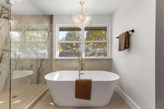 bathroom with tile patterned floors, an inviting chandelier, and shower with separate bathtub