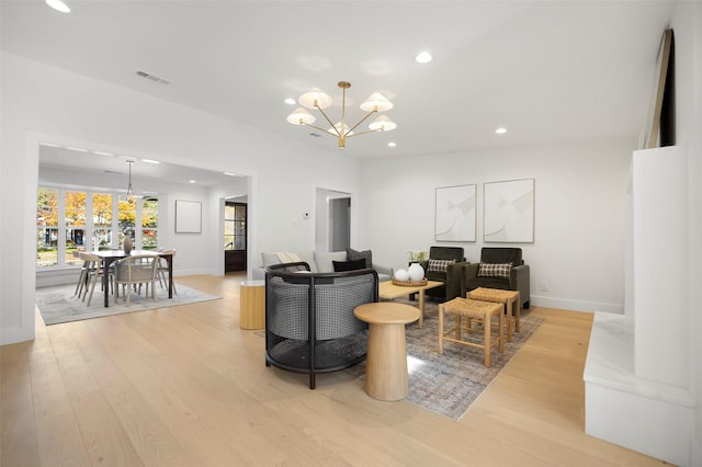 living room with light hardwood / wood-style floors and an inviting chandelier