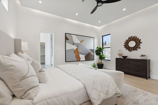 bedroom featuring ceiling fan, a walk in closet, and light hardwood / wood-style flooring