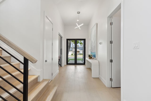 foyer entrance with french doors, a towering ceiling, and light hardwood / wood-style flooring