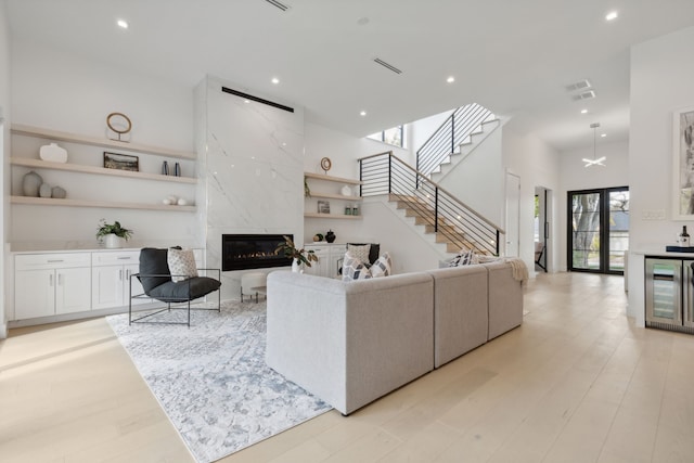 living room featuring a fireplace, light hardwood / wood-style floors, and a high ceiling