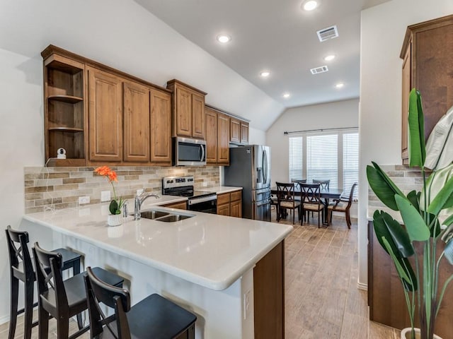 kitchen featuring sink, a breakfast bar area, light hardwood / wood-style flooring, kitchen peninsula, and stainless steel appliances