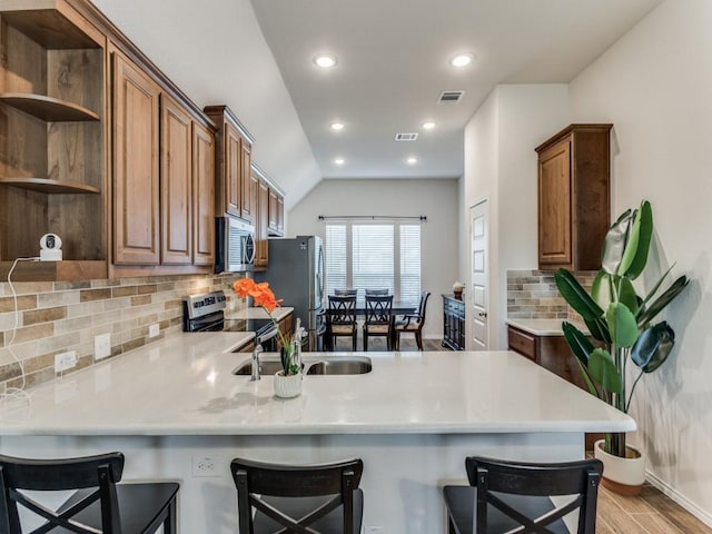 kitchen with a kitchen bar, kitchen peninsula, and appliances with stainless steel finishes