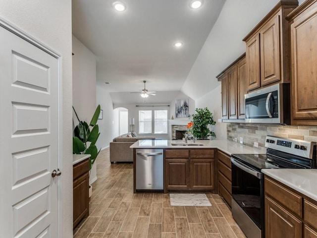 kitchen with ceiling fan, sink, stainless steel appliances, kitchen peninsula, and lofted ceiling