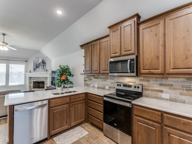 kitchen featuring vaulted ceiling, appliances with stainless steel finishes, sink, decorative backsplash, and kitchen peninsula