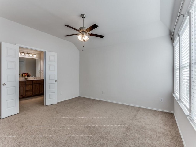 unfurnished bedroom featuring ceiling fan, light colored carpet, lofted ceiling, and connected bathroom