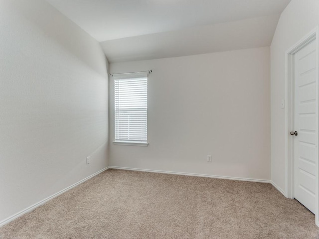 carpeted spare room featuring vaulted ceiling