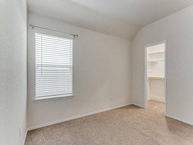 unfurnished room featuring light colored carpet and lofted ceiling