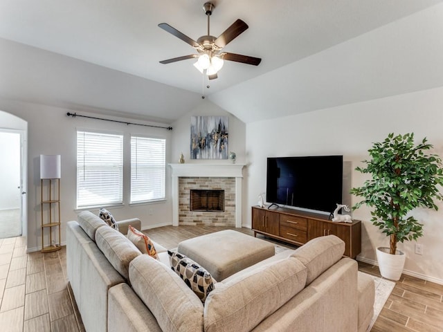 living room with a stone fireplace, ceiling fan, light hardwood / wood-style flooring, and lofted ceiling