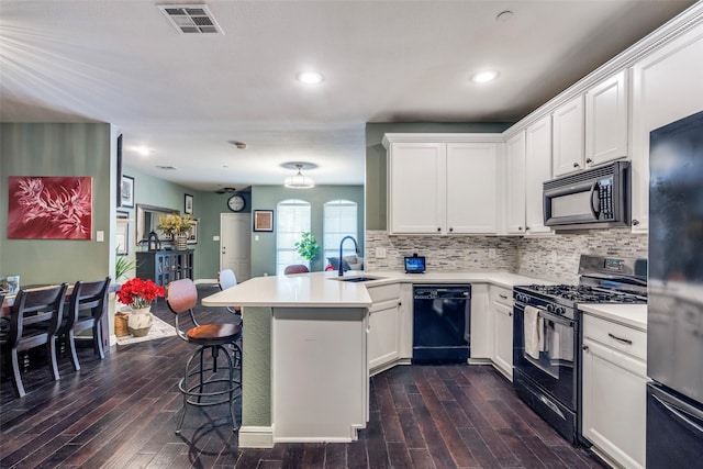 kitchen with black appliances, white cabinetry, sink, a kitchen breakfast bar, and kitchen peninsula