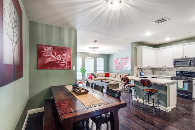 dining space featuring dark hardwood / wood-style floors, sink, and a textured ceiling