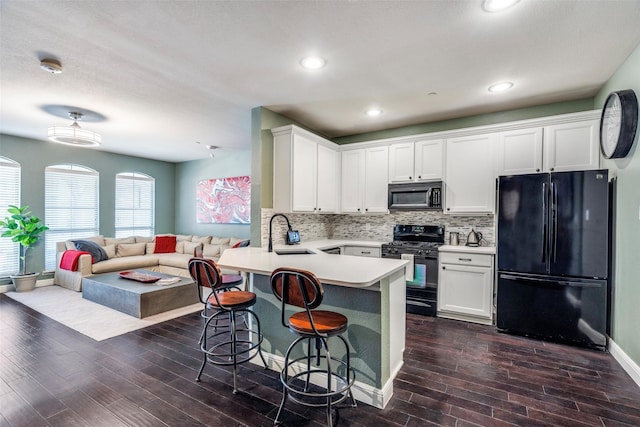 kitchen with sink, a breakfast bar area, white cabinetry, kitchen peninsula, and black appliances