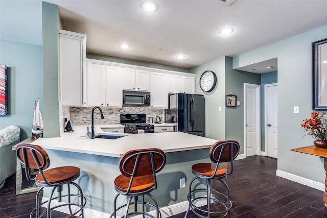 kitchen featuring a breakfast bar, sink, black appliances, kitchen peninsula, and white cabinets