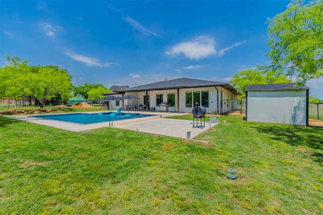 rear view of property featuring a fenced in pool, a patio area, a lawn, and a shed