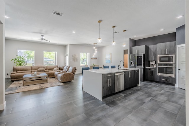 kitchen with ceiling fan, sink, an island with sink, pendant lighting, and appliances with stainless steel finishes