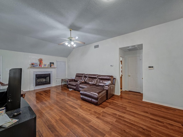 living room featuring hardwood / wood-style flooring, ceiling fan, lofted ceiling, and a textured ceiling