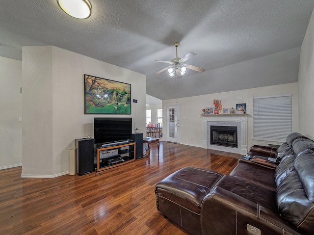 living room with dark hardwood / wood-style flooring, vaulted ceiling, ceiling fan, and a textured ceiling