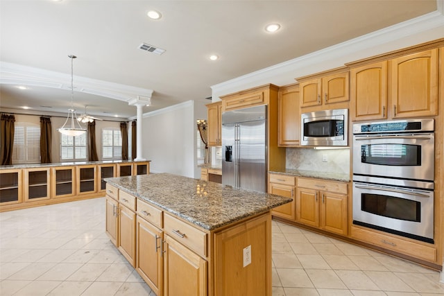 kitchen with ornate columns, a center island, built in appliances, pendant lighting, and ornamental molding