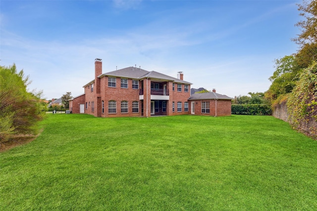 rear view of property with a yard and a balcony