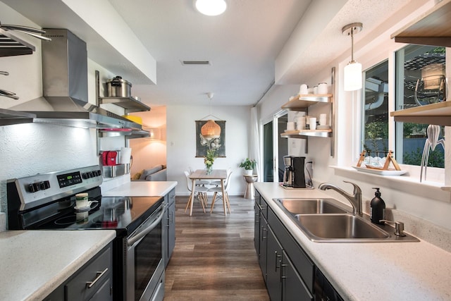 kitchen with electric stove, sink, wall chimney exhaust hood, decorative light fixtures, and dark hardwood / wood-style flooring