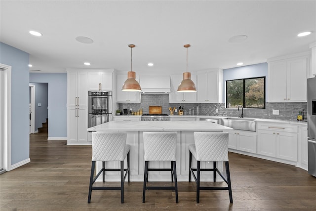 kitchen featuring white cabinetry, a kitchen island, sink, and pendant lighting