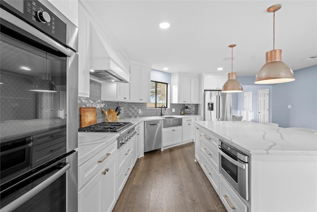 kitchen featuring sink, hanging light fixtures, stainless steel appliances, a kitchen island, and white cabinets