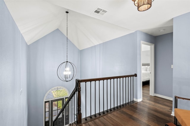 hallway featuring dark hardwood / wood-style floors, high vaulted ceiling, and a notable chandelier