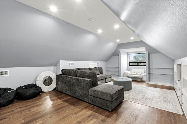 interior space featuring wood-type flooring, a textured ceiling, and vaulted ceiling