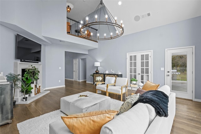 living room featuring french doors, hardwood / wood-style floors, a chandelier, and a high ceiling