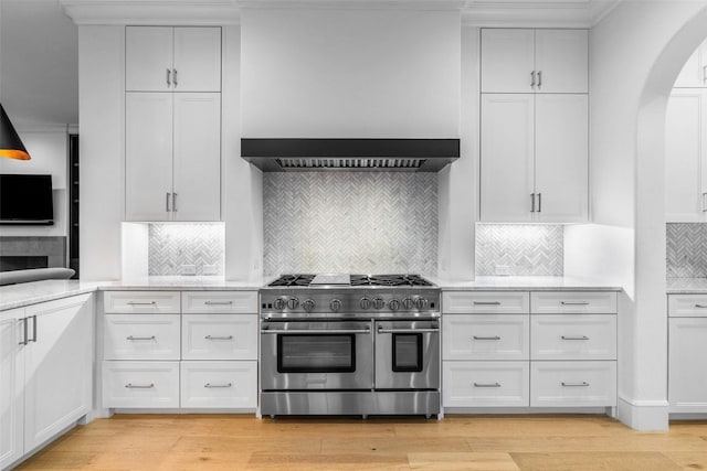 kitchen featuring tasteful backsplash, white cabinets, double oven range, and light hardwood / wood-style floors